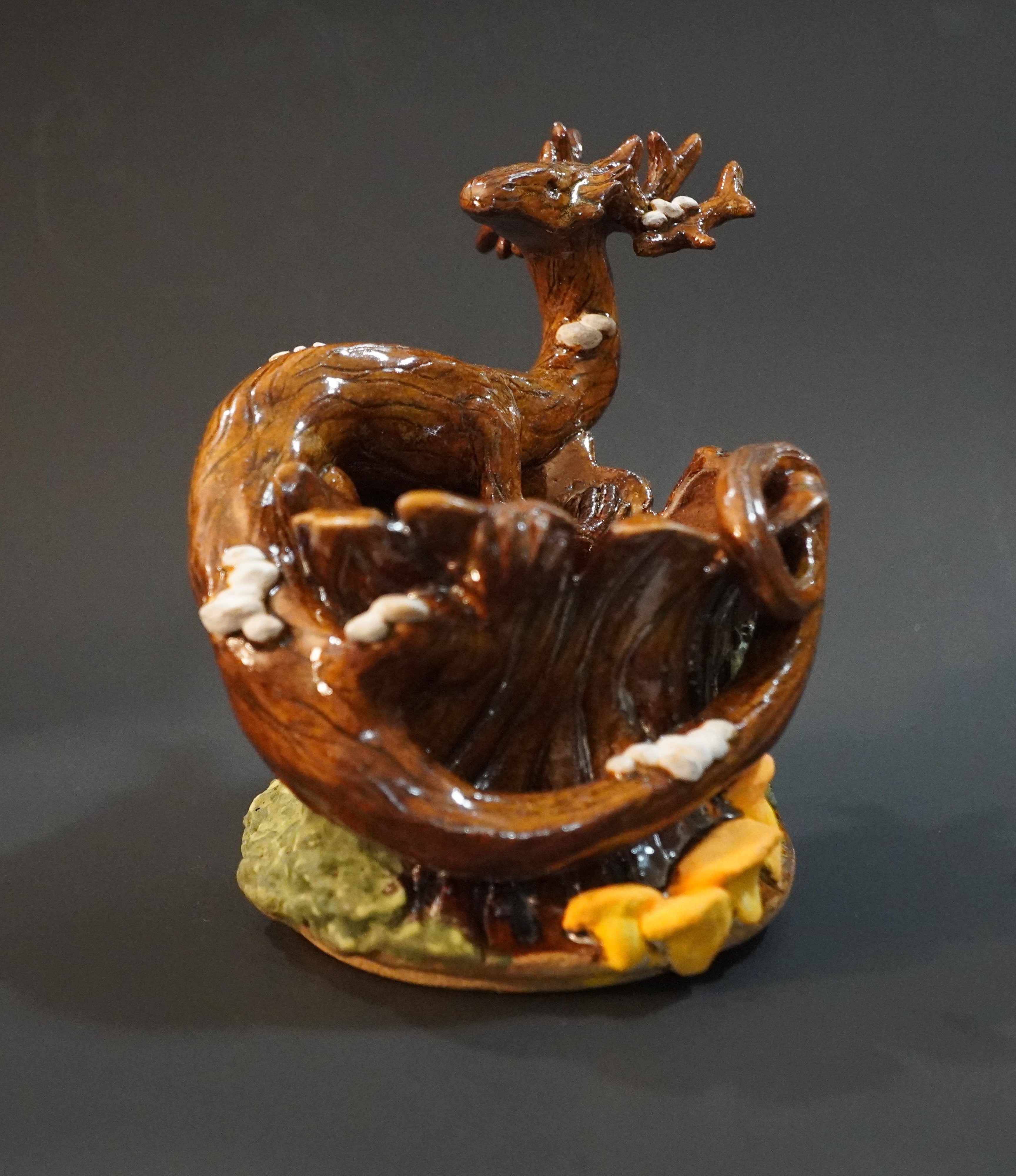 Ceramic sculpture of a tree dragon on a stump, covered in moss and mushrooms