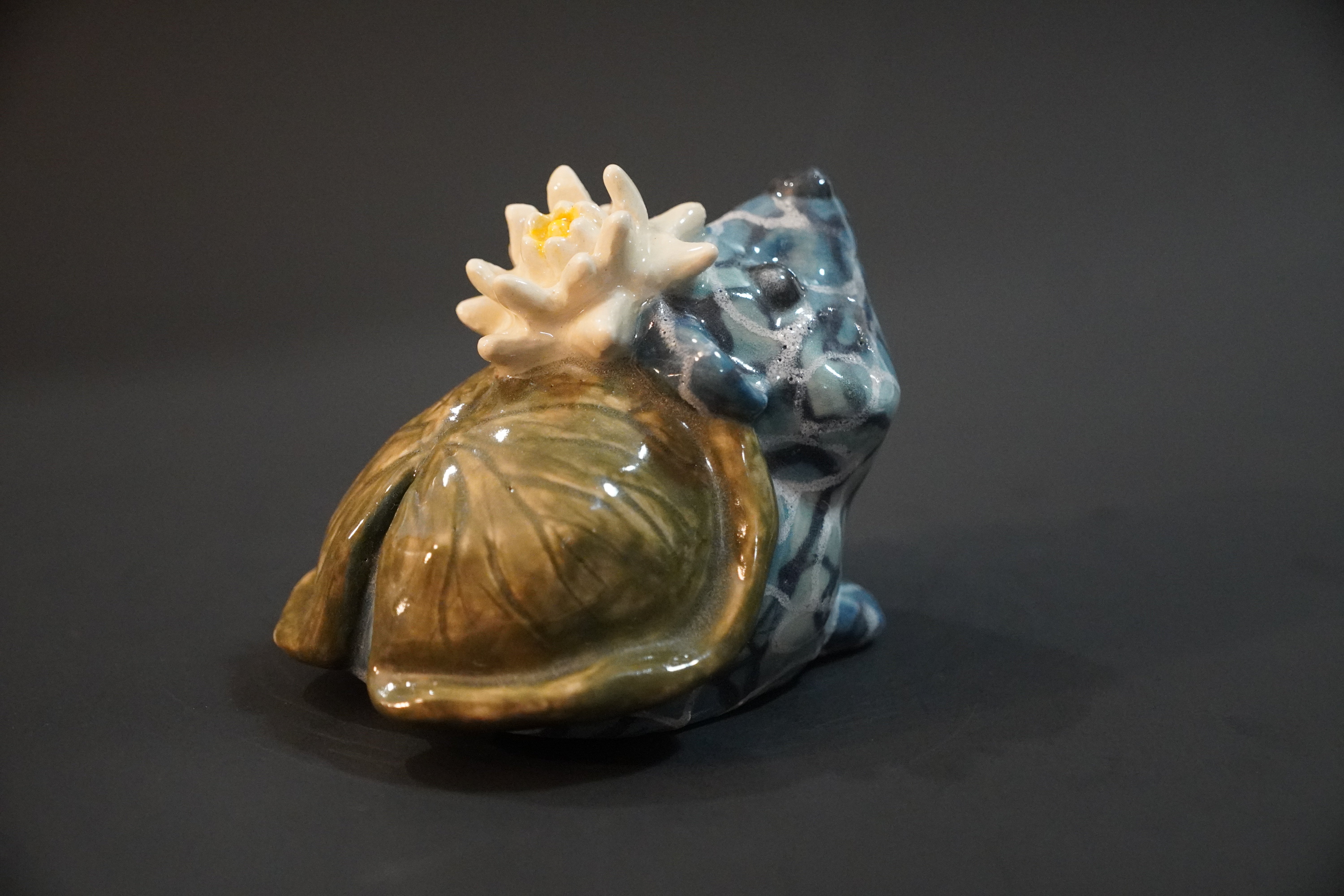 Ceramic sculpture of a hedgehog where its body is water and a waterlily pad and flower are its back