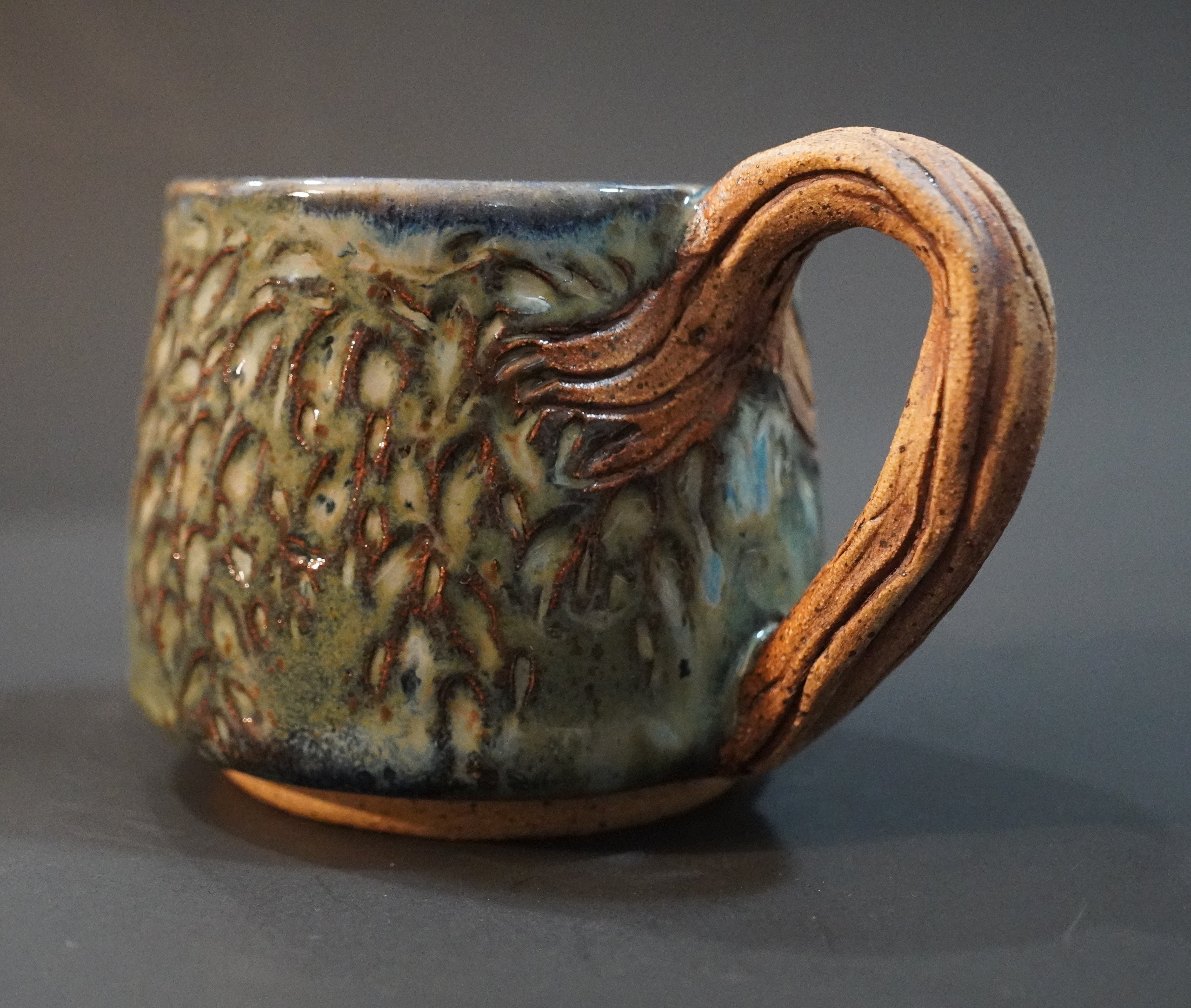 Denim glazed ceramic mug with a weeping willow tree trunk as the handle and leaves carved into the body of the mug